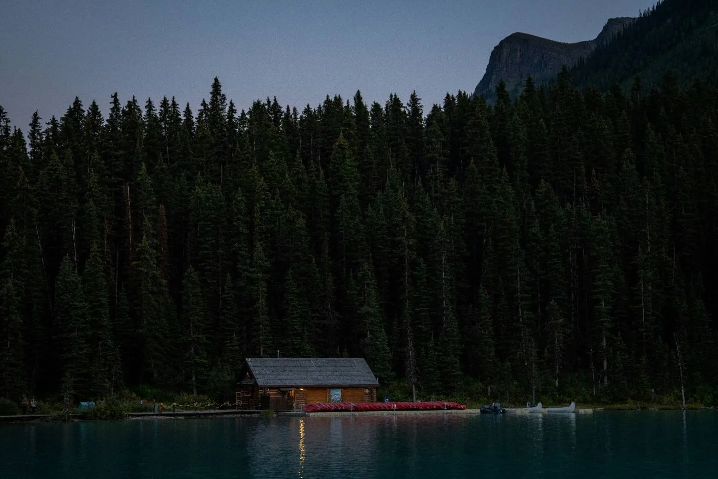 A cabin on a lake below mountains