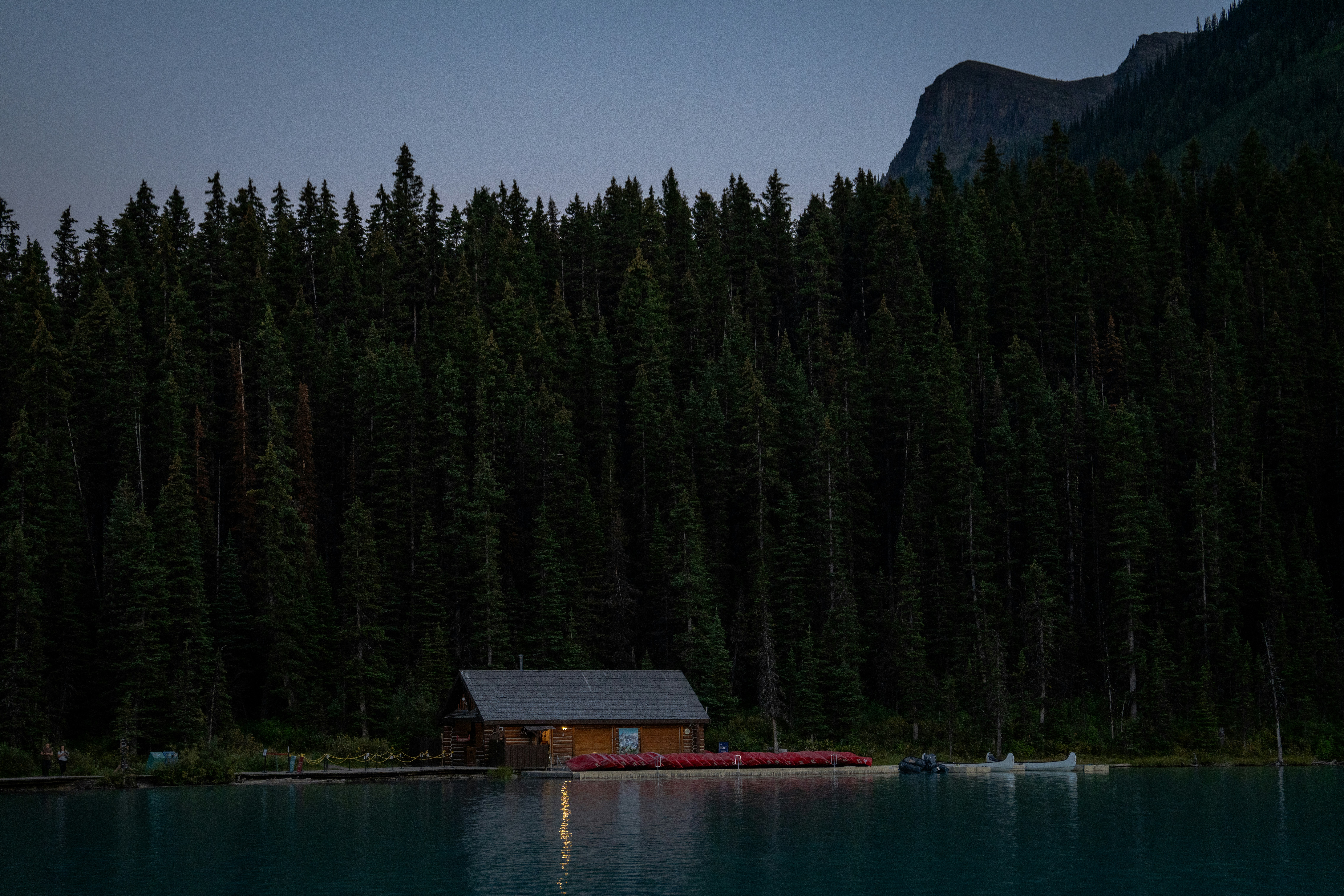 A cabin on a lake below mountains